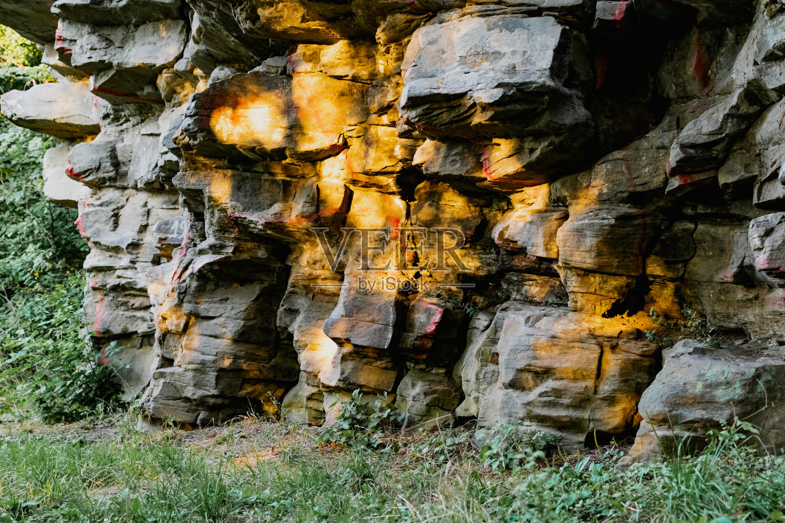 立体的石头在夕阳的光线下形成不同形状的岩石。带有白色条纹的古老岩层照片摄影图片