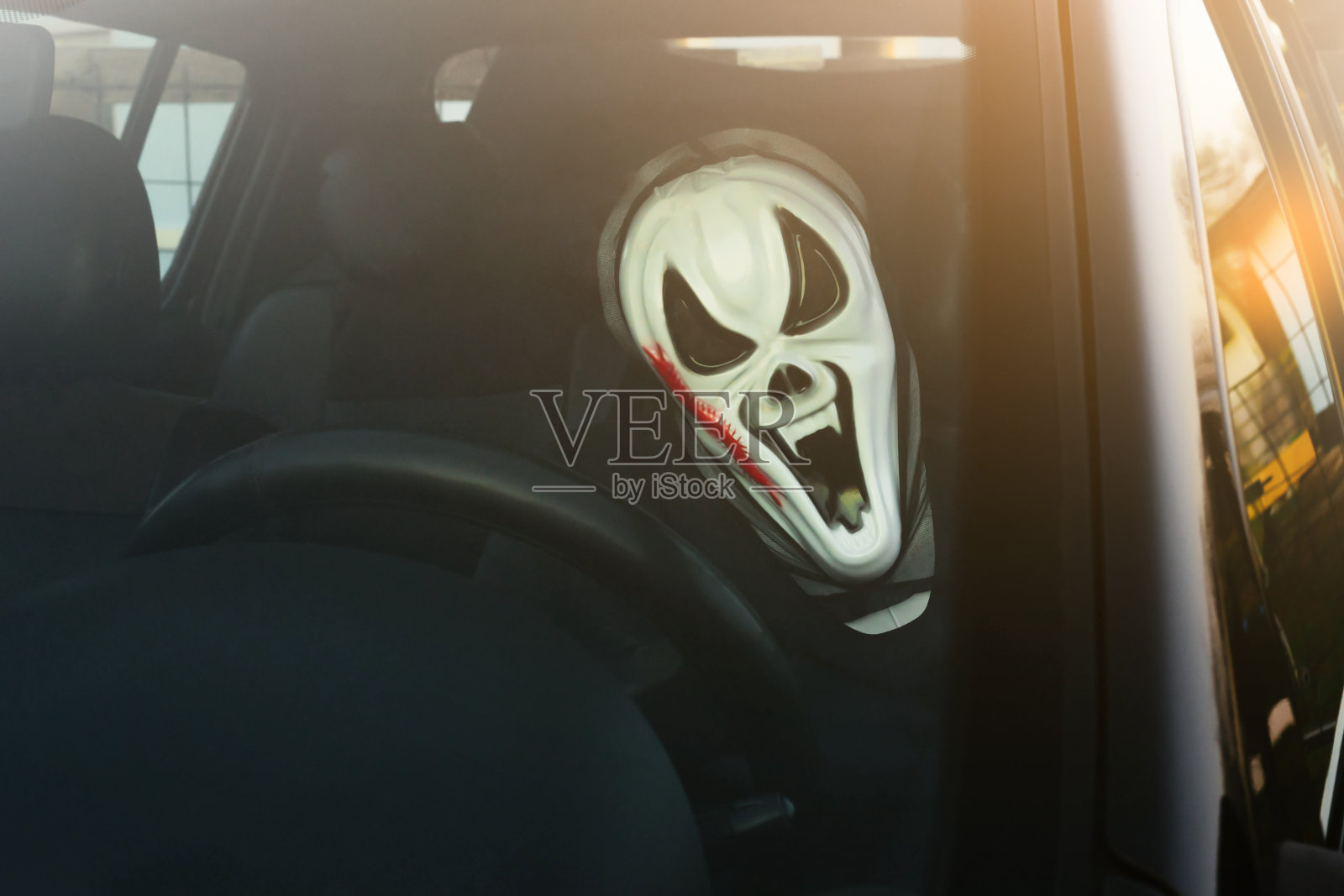 万圣节。一名戴着可怕面具的男子坐在驾驶座上收获南瓜和恐惧。照片摄影图片