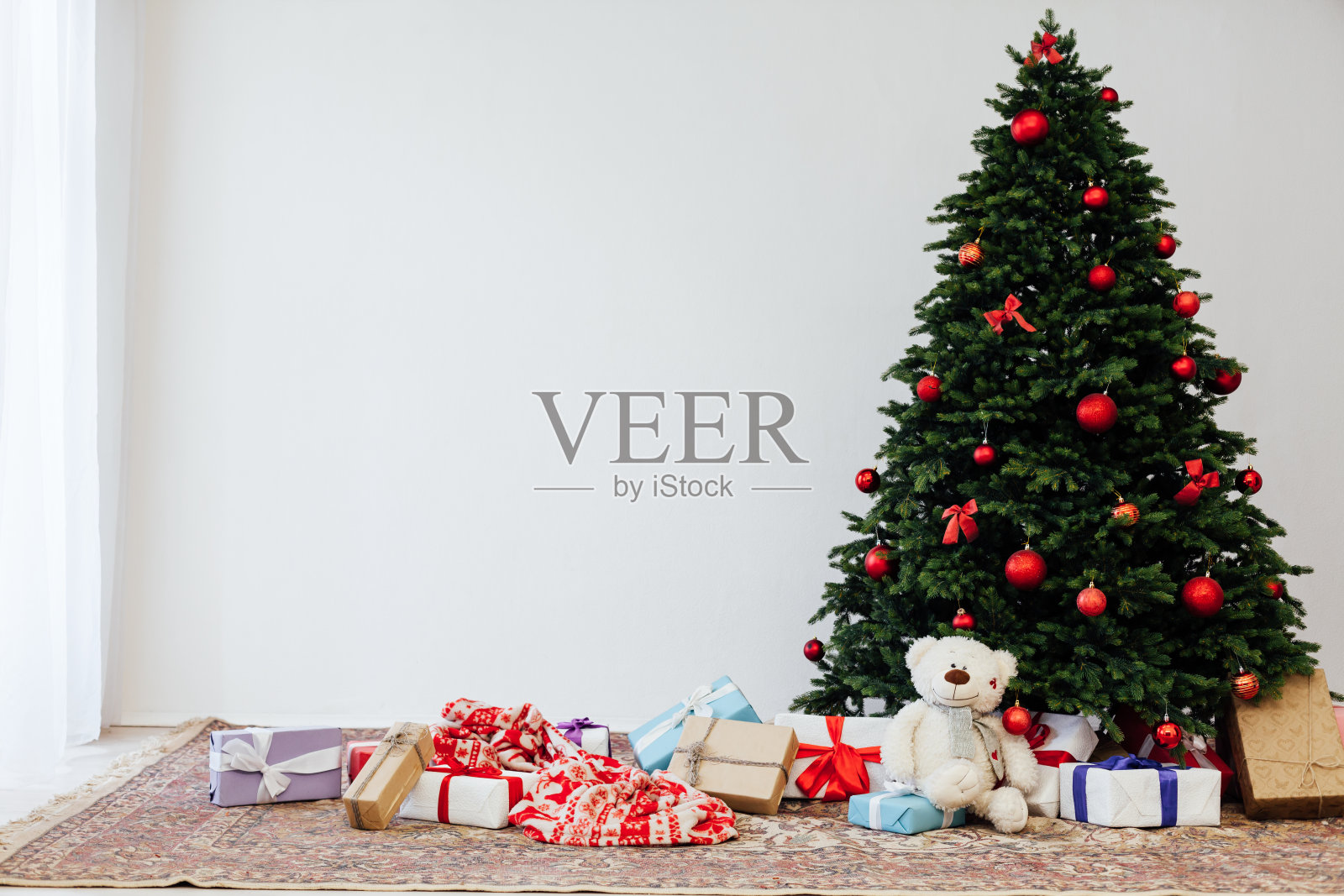 白色房间的内部是一棵绿色的圣诞树,上面挂着红色的礼物,作为新年的装饰照片摄影图片