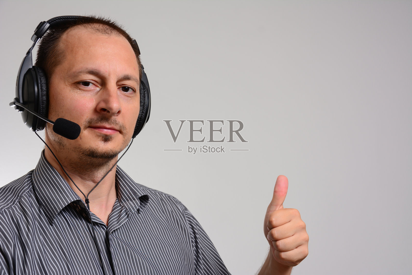 男接线员竖起大拇指做手势。照片摄影图片