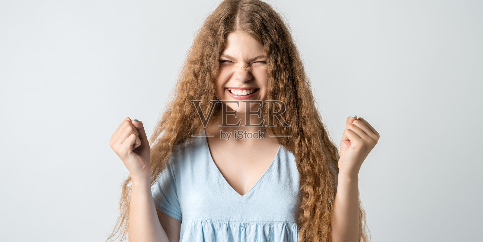 快乐的女孩紧握双拳,庆祝成功,在白色背景下隔离照片摄影图片