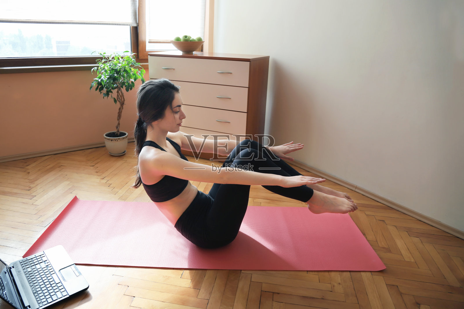 年轻女子做运动在家里与互联网的帮助照片摄影图片