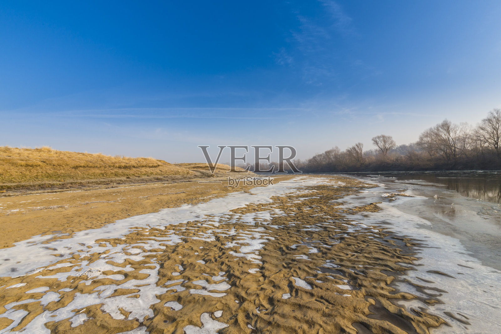 美丽的沙丘覆盖着霜和新雪,在一个荒凉的河岸上,在冬天照片摄影图片