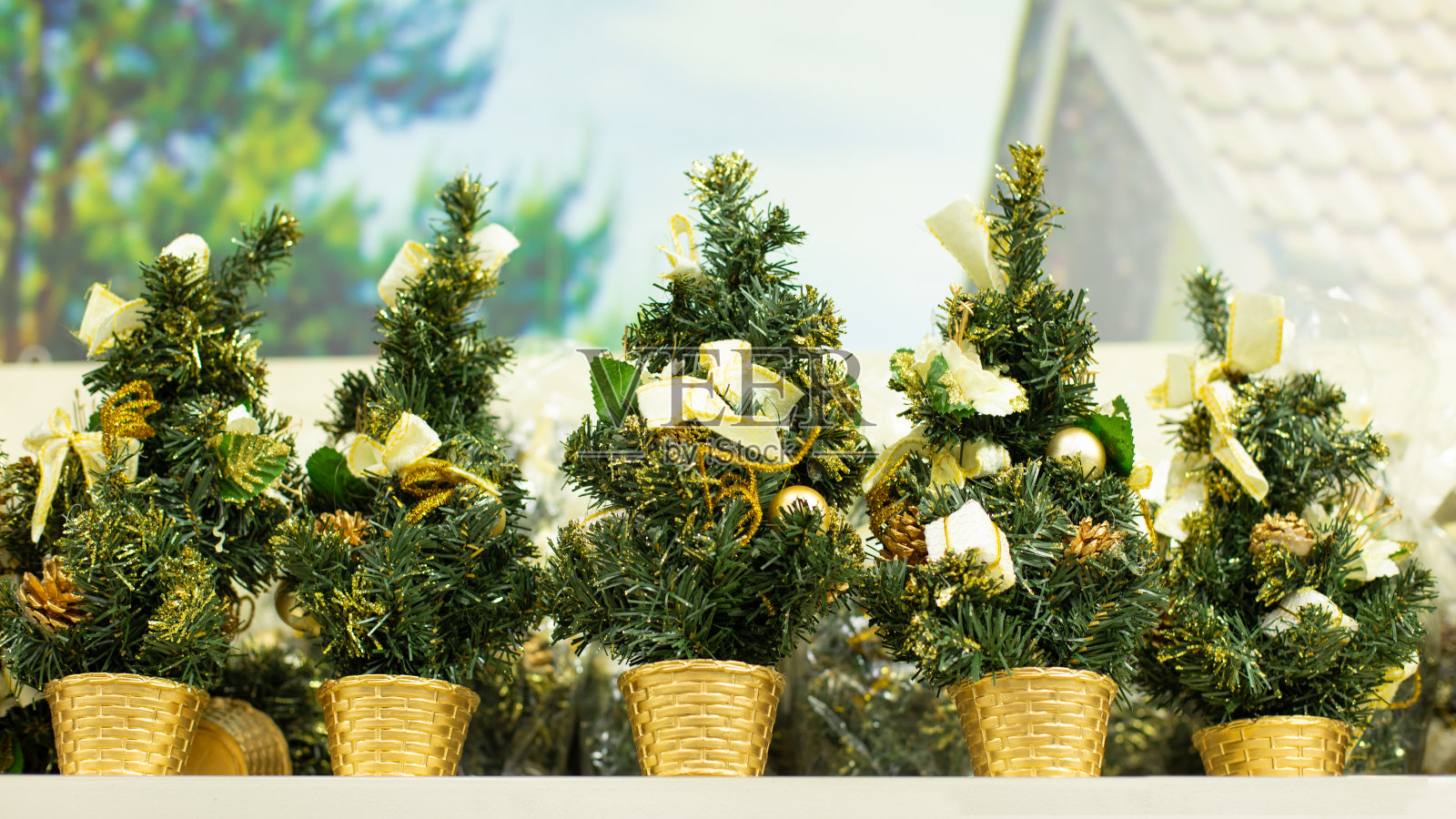 一棵小装饰圣诞树作为礼物,一套用金色装饰的圣诞树。背景明亮的圣诞装饰,人造圣诞树与松果照片摄影图片