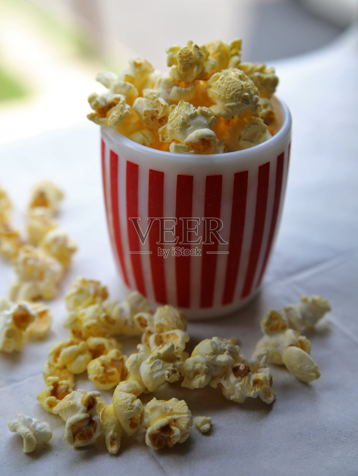 条纹杯上的黄色爆米花。照片摄影图片