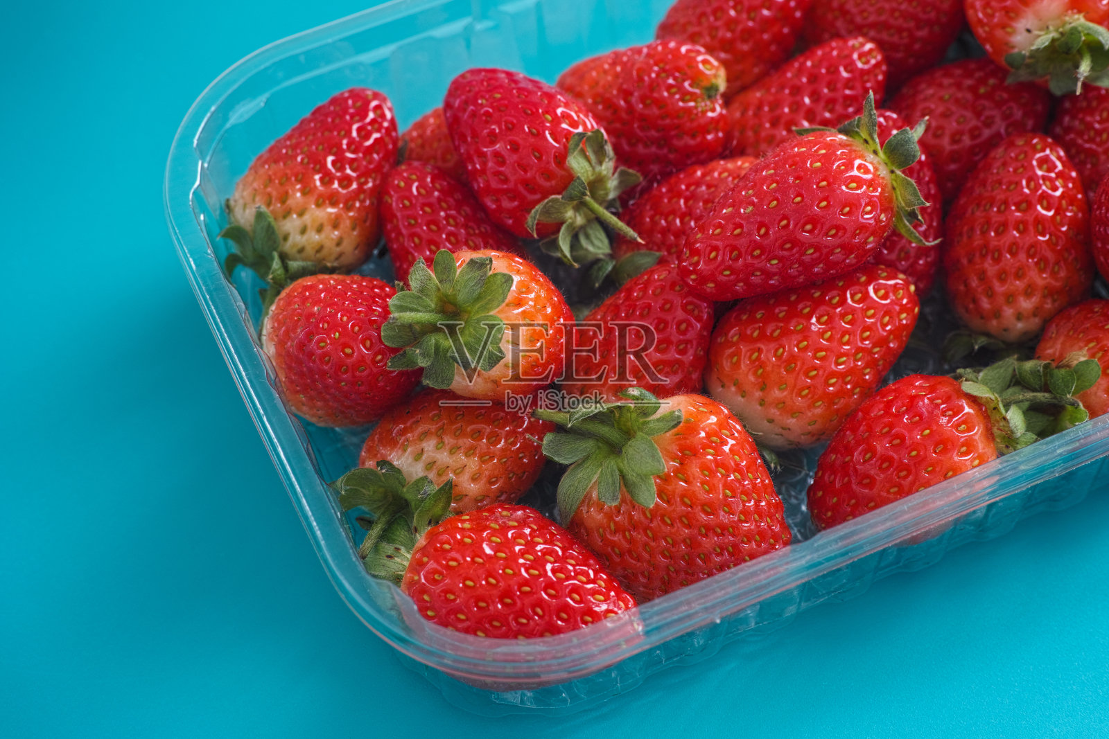 新鲜收获的草莓装在塑料容器里照片摄影图片