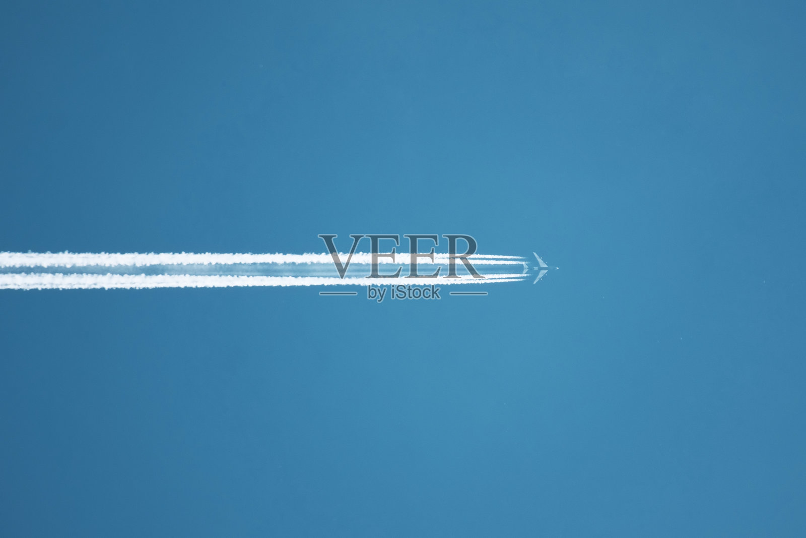 在晴朗的蓝天下,近距离观察飞机的轨迹。照片摄影图片