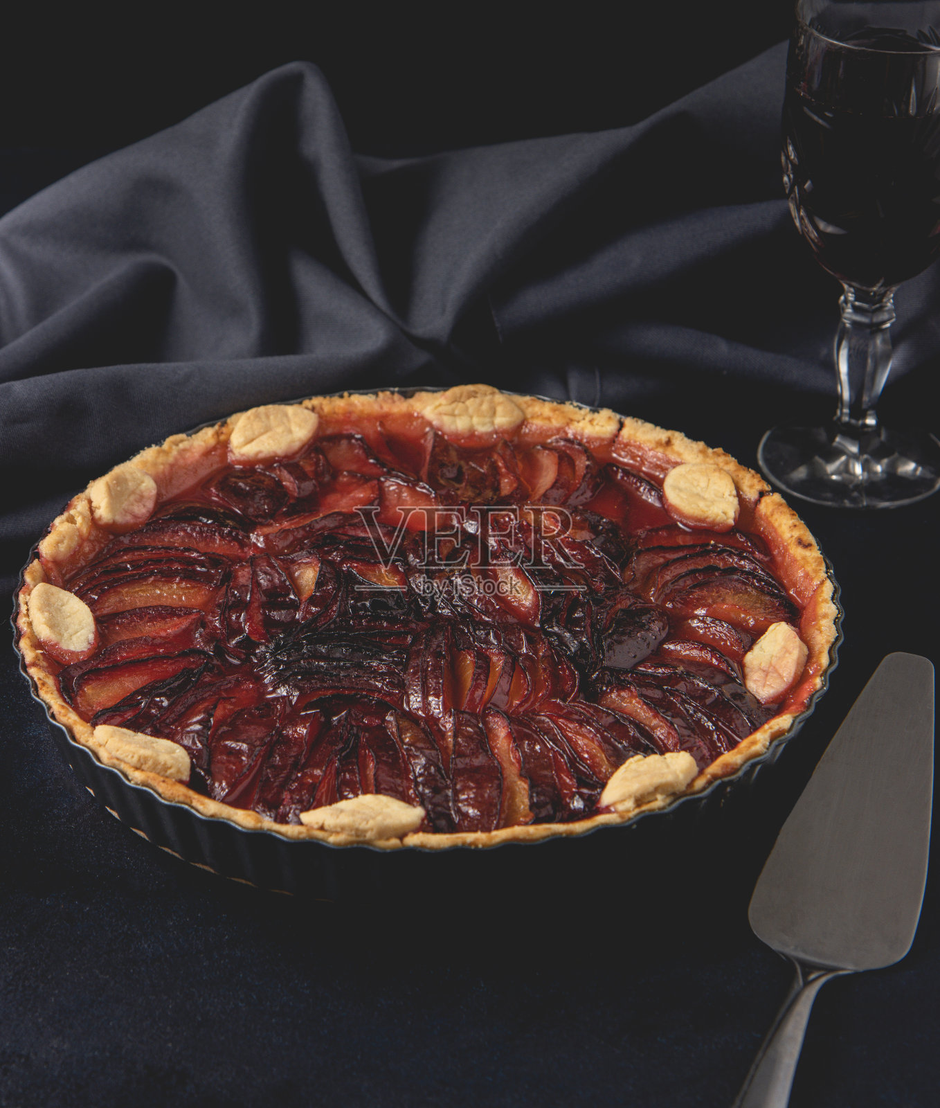 用李子、薰衣草和糖做的自制派,放在深色的背景上。梅子烤挞。前视图。照片摄影图片