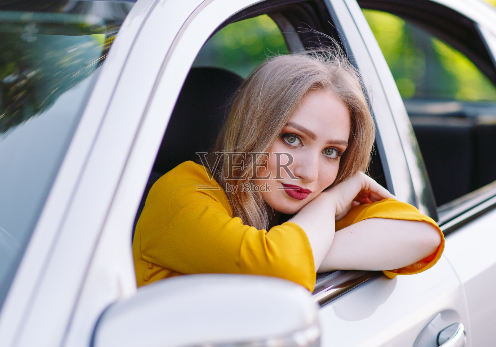 一个年轻漂亮的女孩正在开车。照片摄影图片