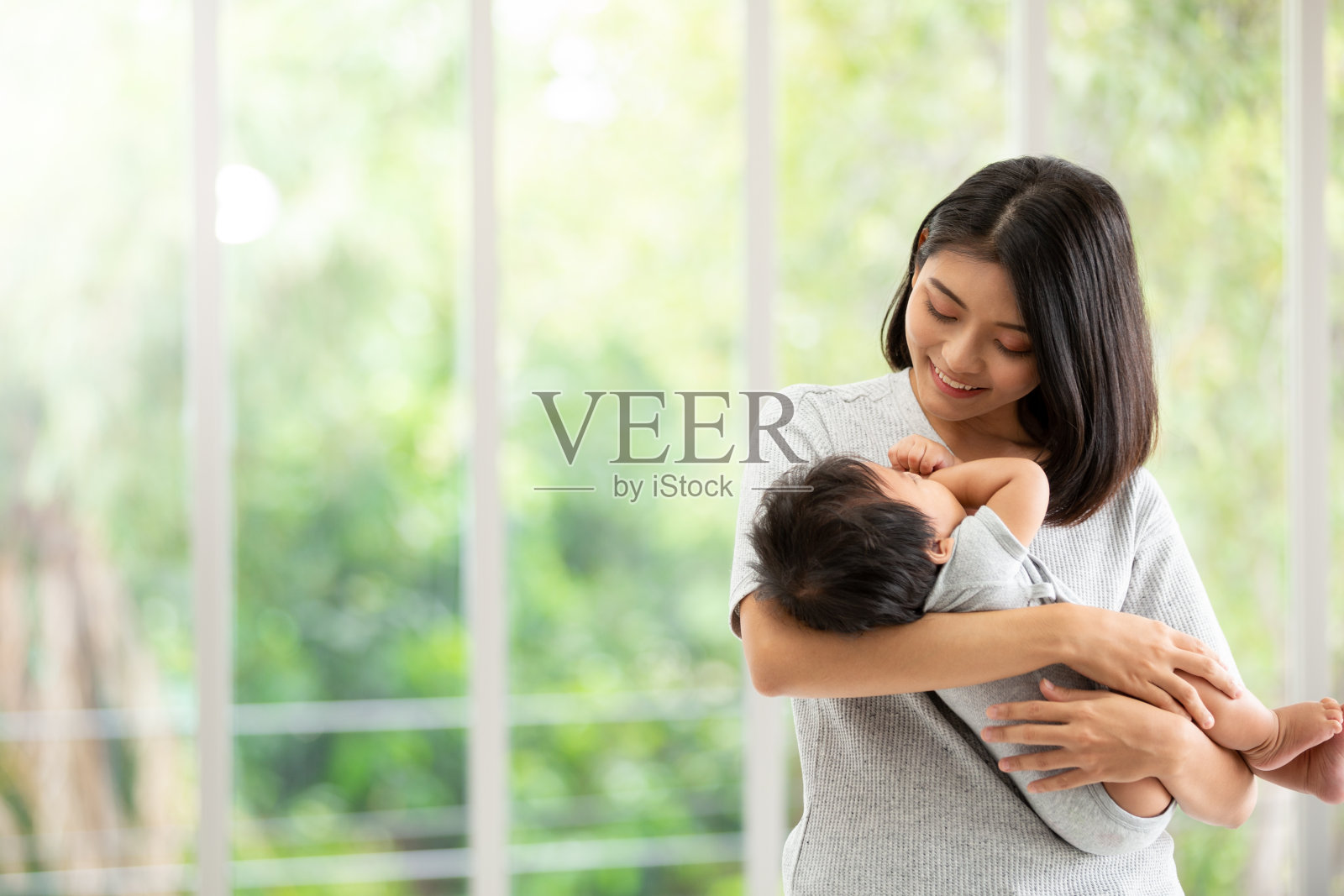 年轻美丽的亚洲母亲与新生儿在客厅的肖像。健康医疗爱亚洲女性生活方式母亲节理念与复制空间。照片摄影图片