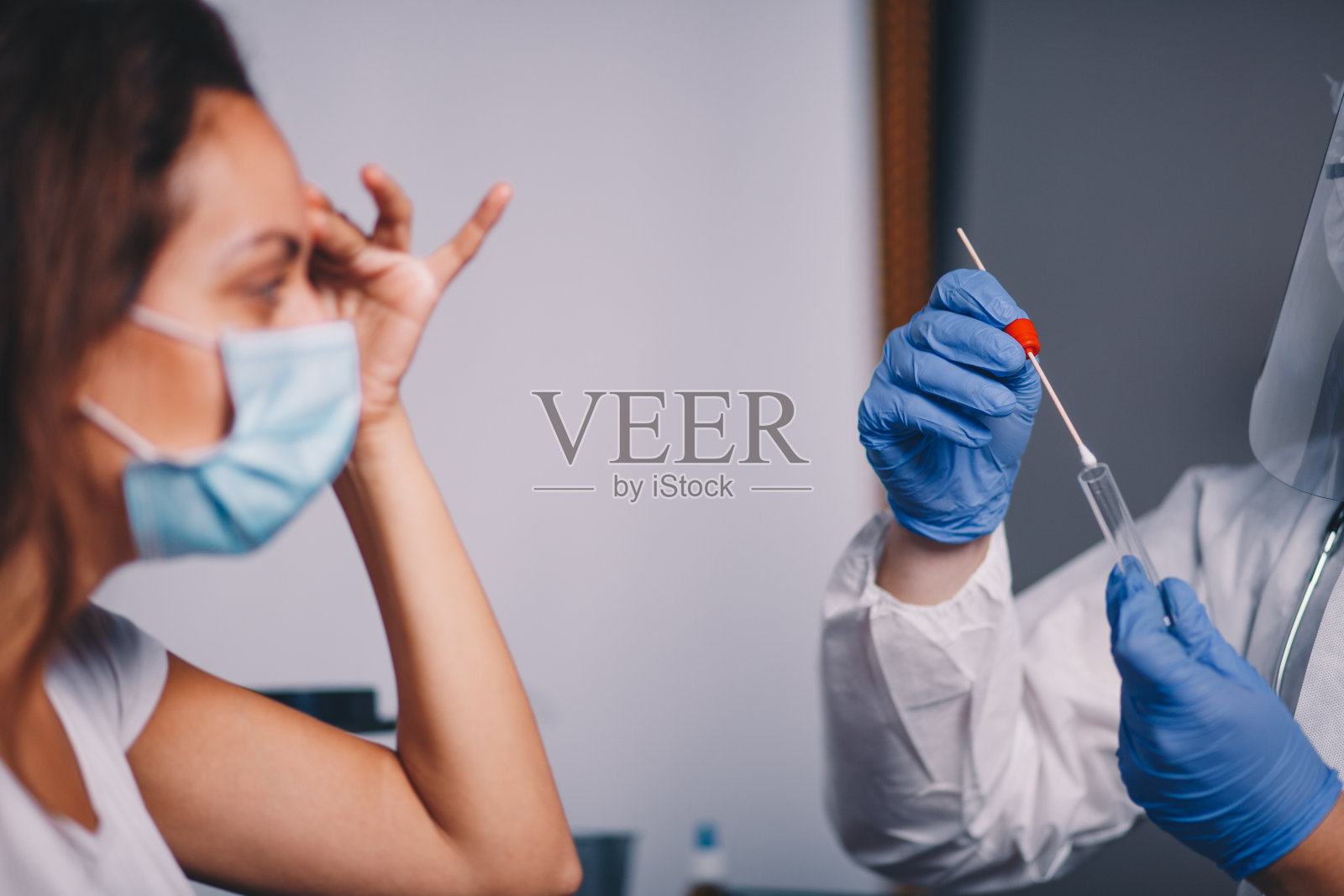 男医生带著防护装备,从女病人身上取棉签作化验照片摄影图片