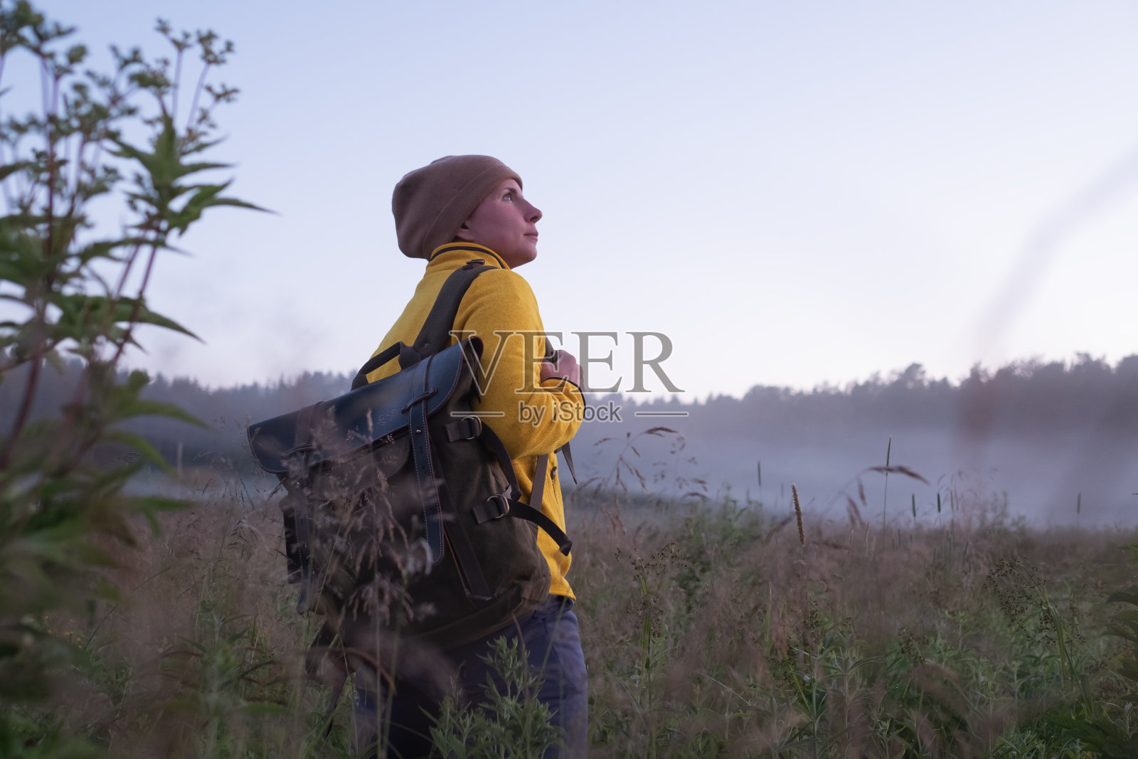 一个白人女人独自走在田野里。女孩在运动服装徒步背包。照片摄影图片