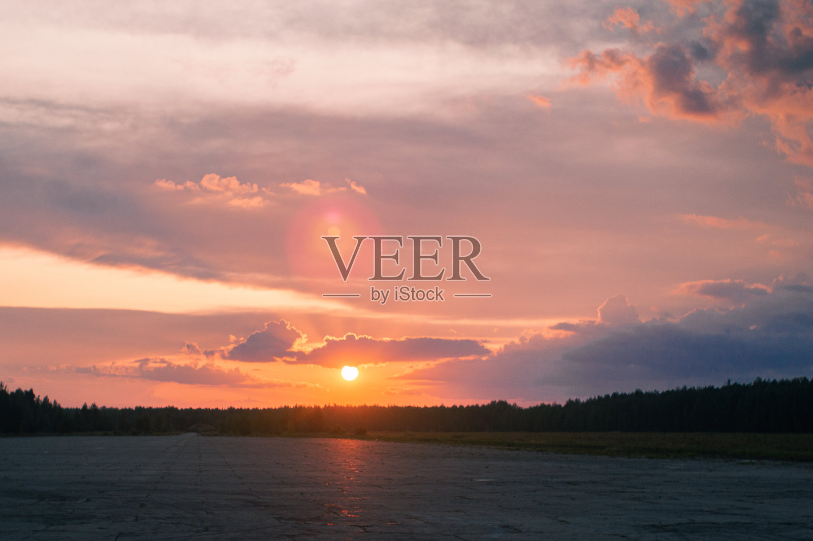 粉红色的日落在一个废弃的田野附近的一条空的道路照片摄影图片