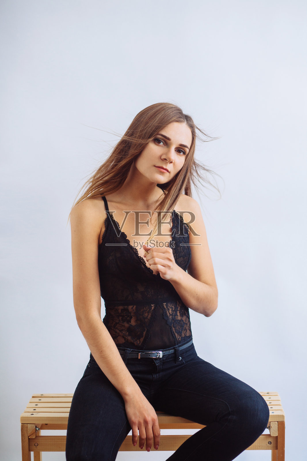 年轻迷人的女孩穿着黑色上衣和牛仔裤在一个明亮的背景照片摄影图片