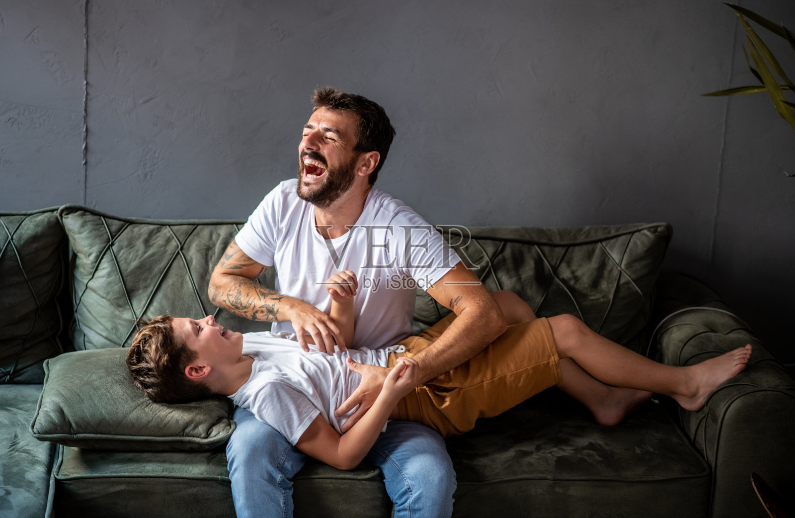 父亲和儿子一起呆在家里的客厅,父亲胳肢他的儿子照片摄影图片