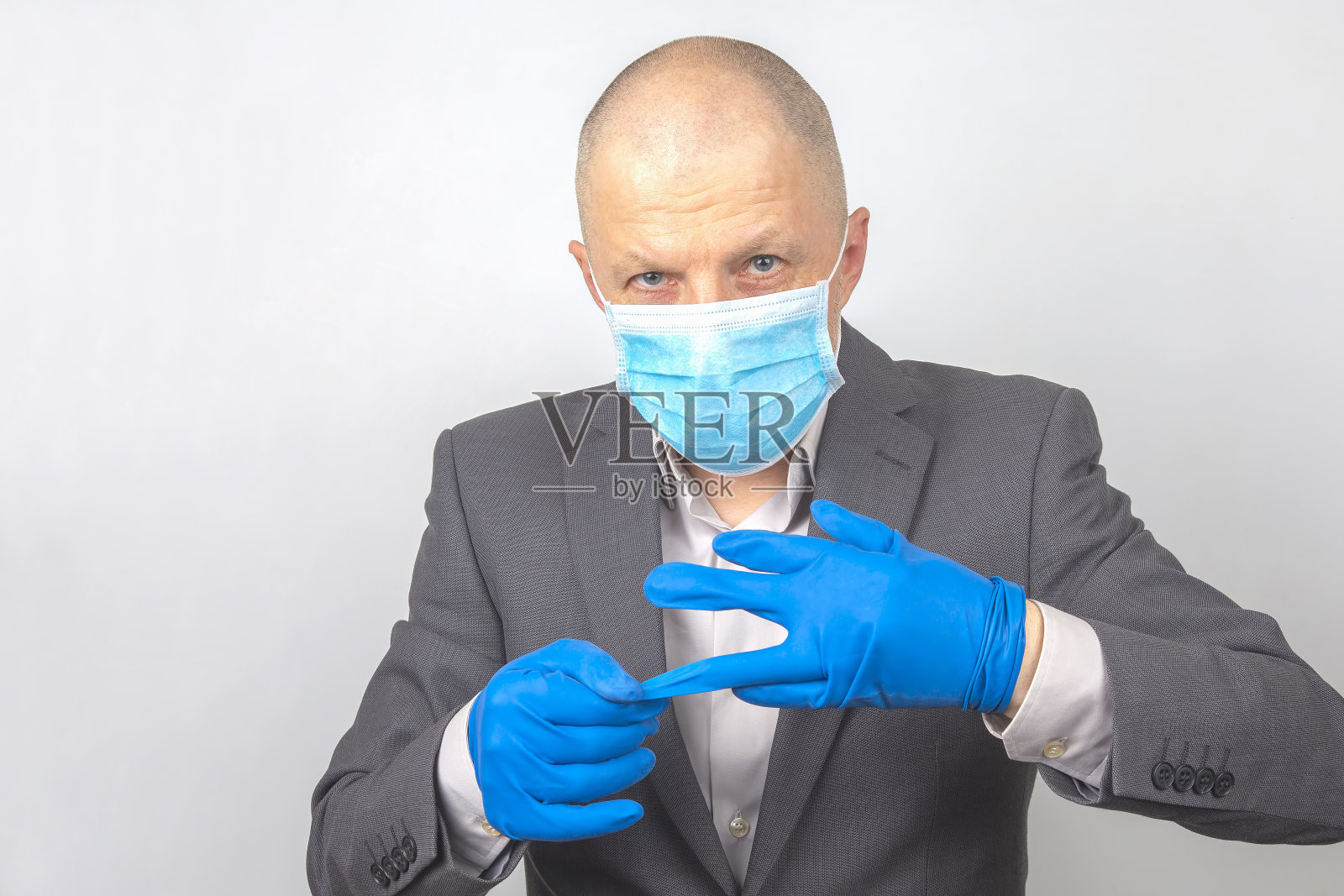 戴医用口罩的商人脱下手上的防护手套。病毒检疫照片摄影图片