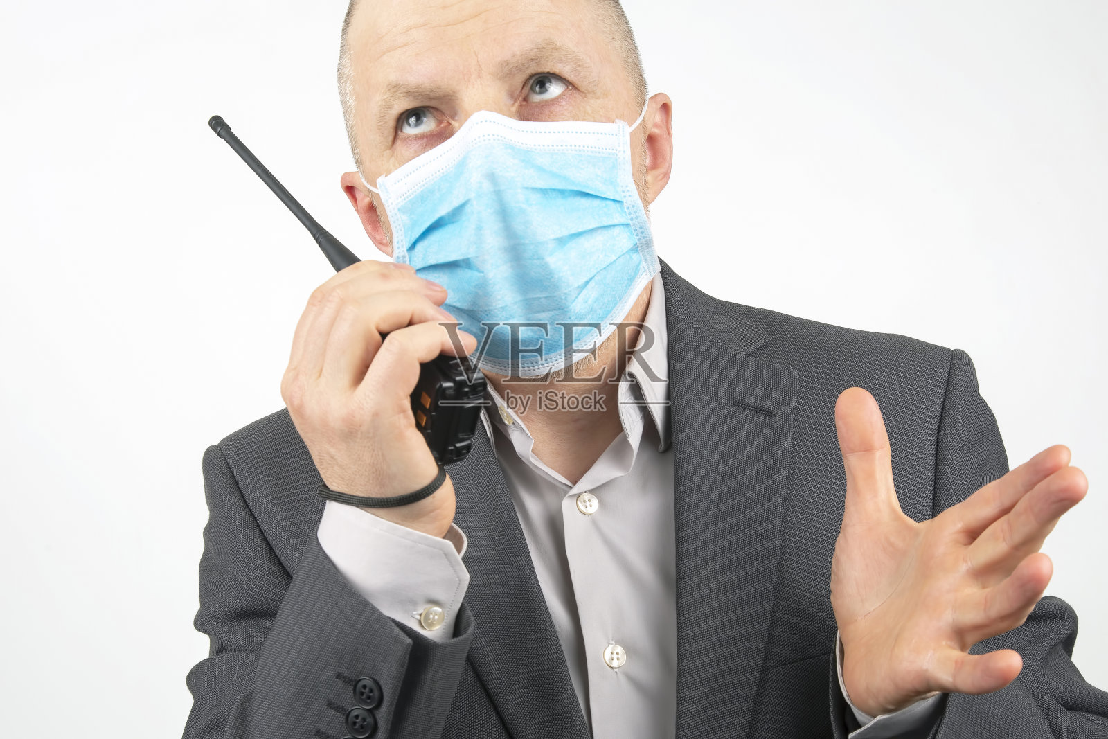 戴医用口罩的商人用对讲机说话照片摄影图片