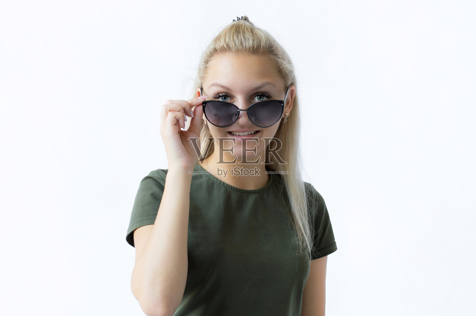 在一个孤立的白色背景上有一个金发女孩的肖像,她手里拿着太阳镜,望着远方,梦想着休息照片摄影图片