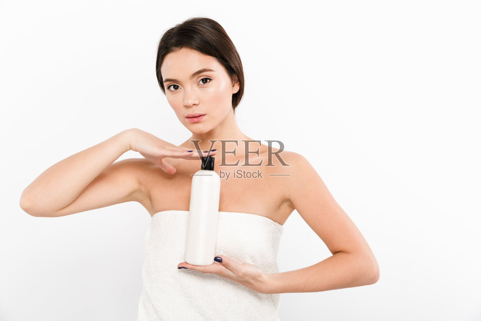 美丽的照片亚洲年轻女子在毛巾拿着瓶子与保湿霜或油在手上,孤立在白色的背景照片摄影图片