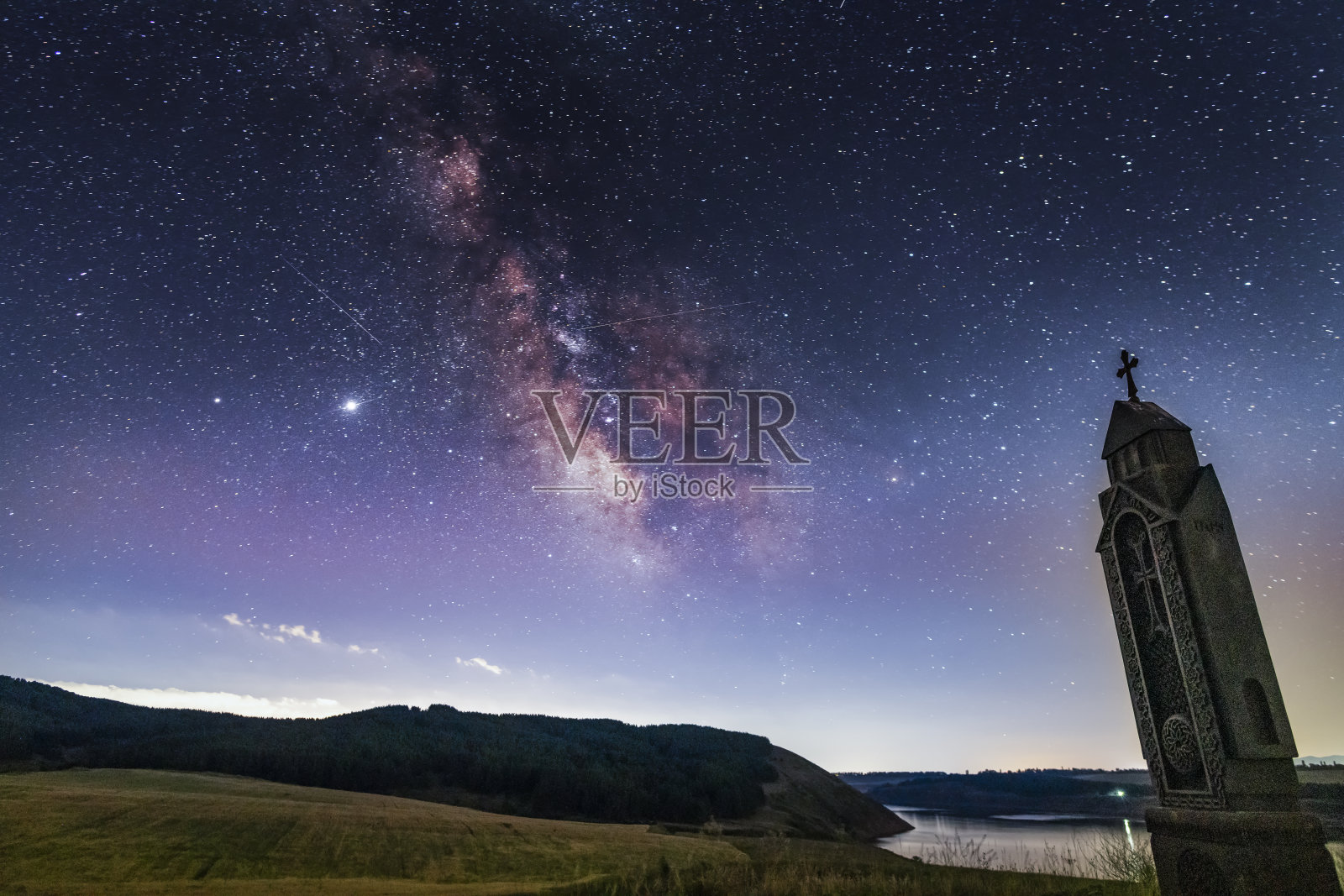 美丽的夜景,星空与明亮的银河湖上的银河。亚美尼亚的基督教纪念碑。天文背景。照片摄影图片