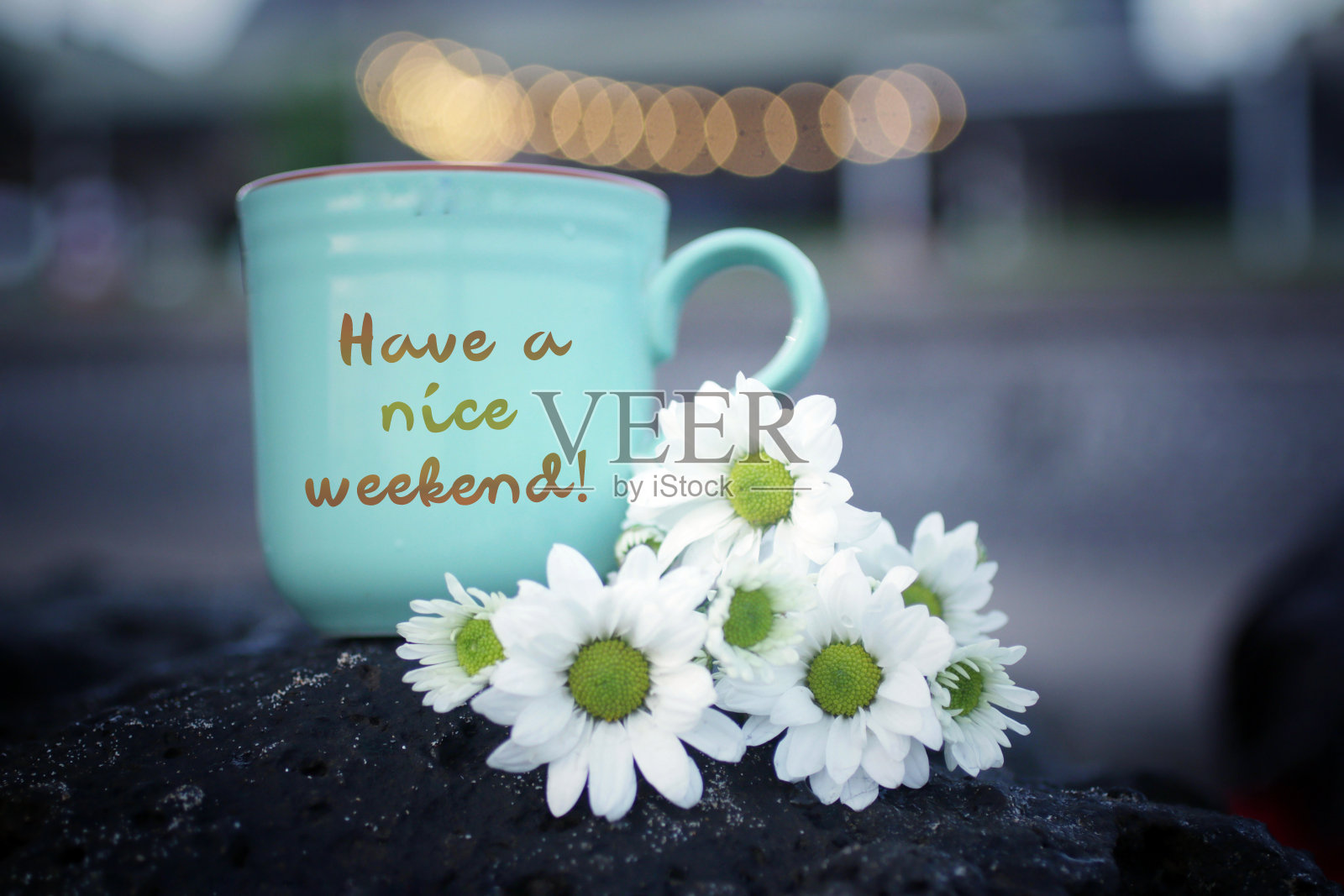 有一个美好的周末概念,咖啡杯和白色雏菊花在淡淡的散景背景。照片摄影图片