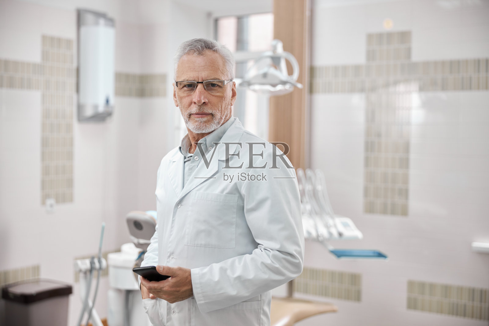 专业牙医骄傲地站在他的办公室里照片摄影图片