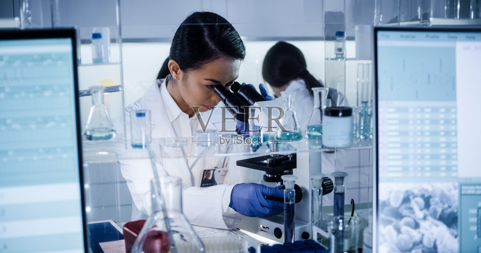 研究DNA序列的女医生。使用显微镜照片摄影图片