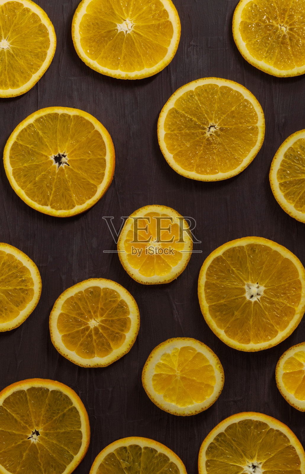 熟透的橙子切成圆形多汁的薄片,躺在黑色的背景上照片摄影图片