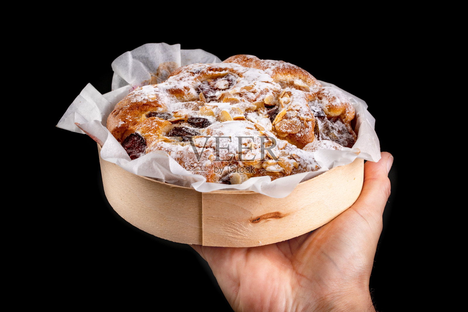 美味的水果蛋糕在纸模中握在你的手掌。供食用的甜点。黑暗的背景。照片摄影图片