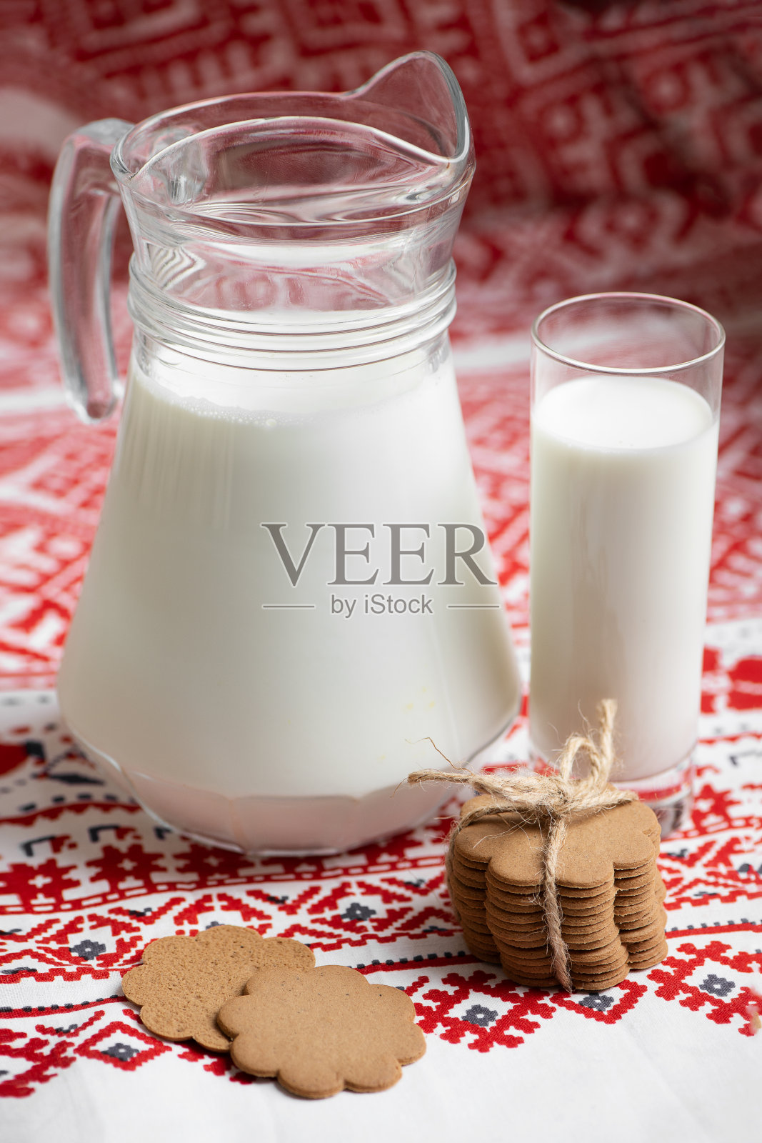壶和杯子牛奶和饼干在红色图案的桌布上照片摄影图片