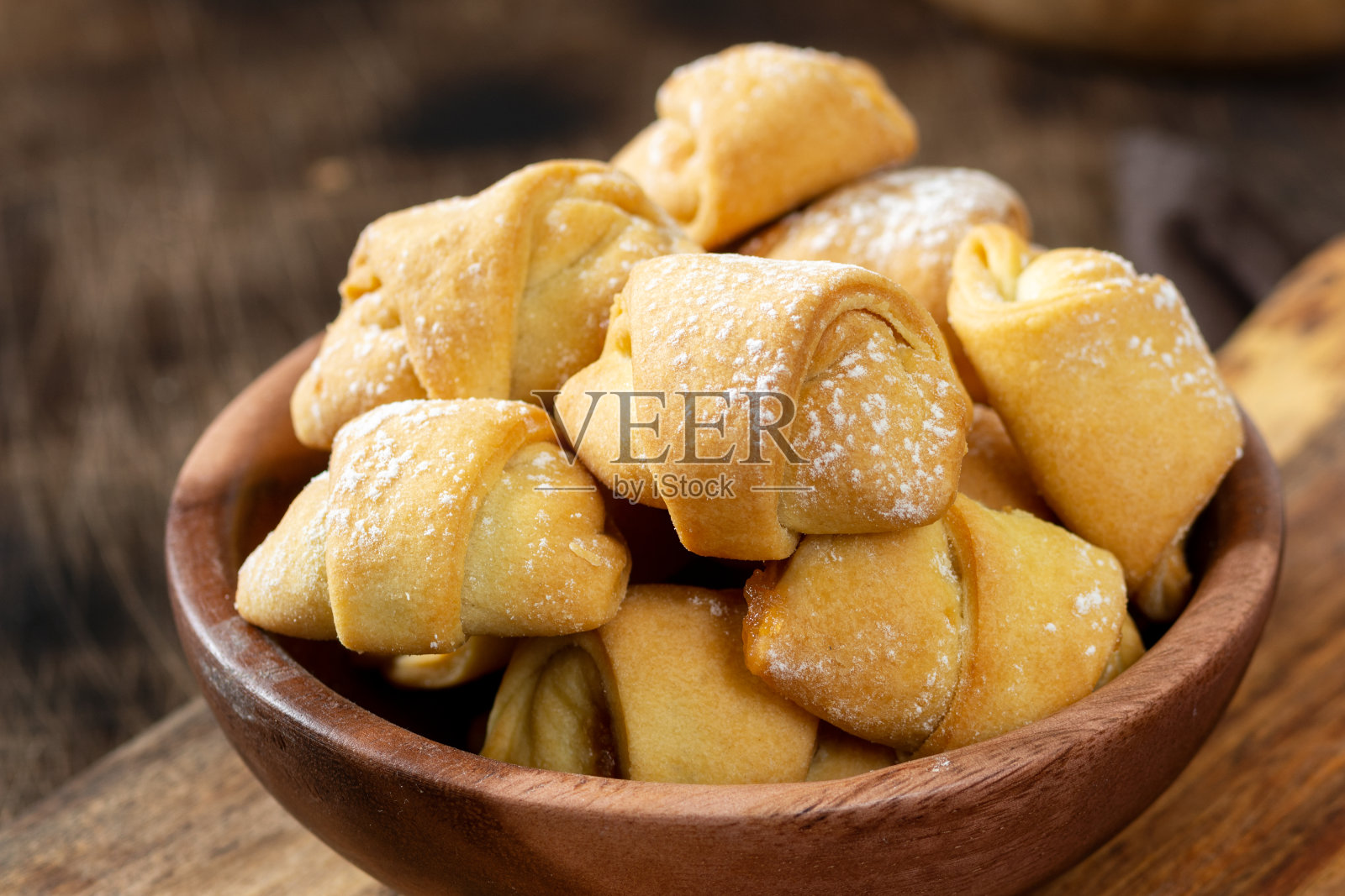 大量的百吉饼。棕色桌子上木盘子里的酥皮。饼干关闭照片摄影图片