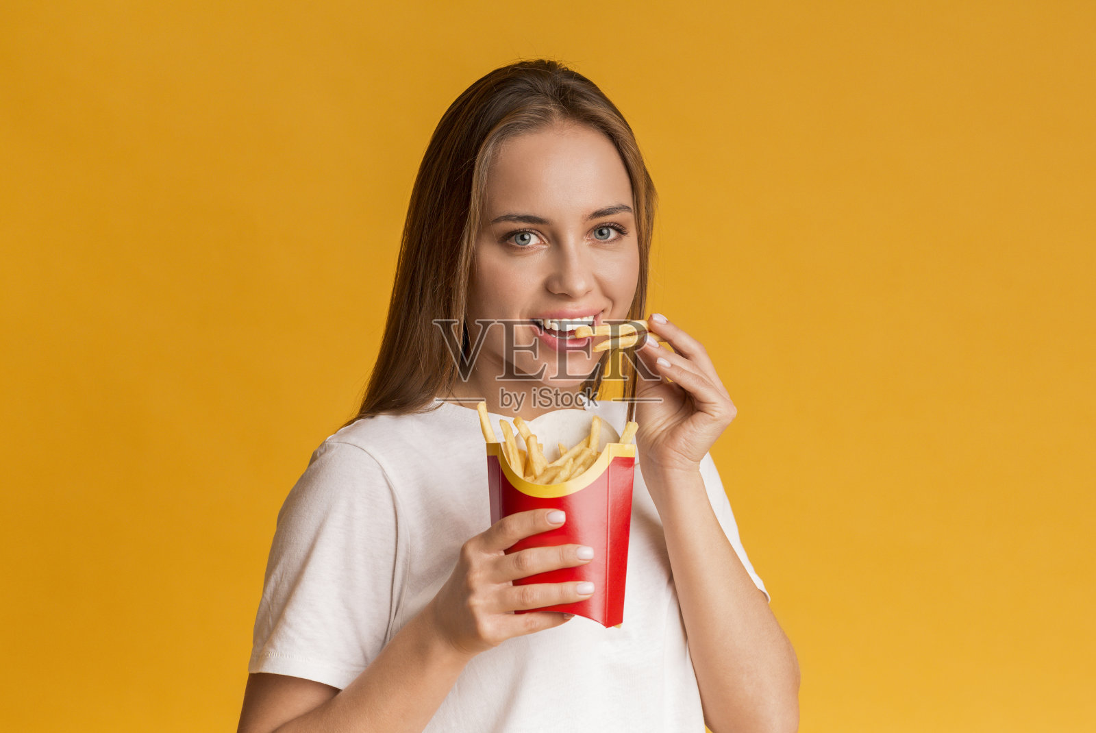 快乐的年轻女子吃薯条土豆的肖像照片摄影图片