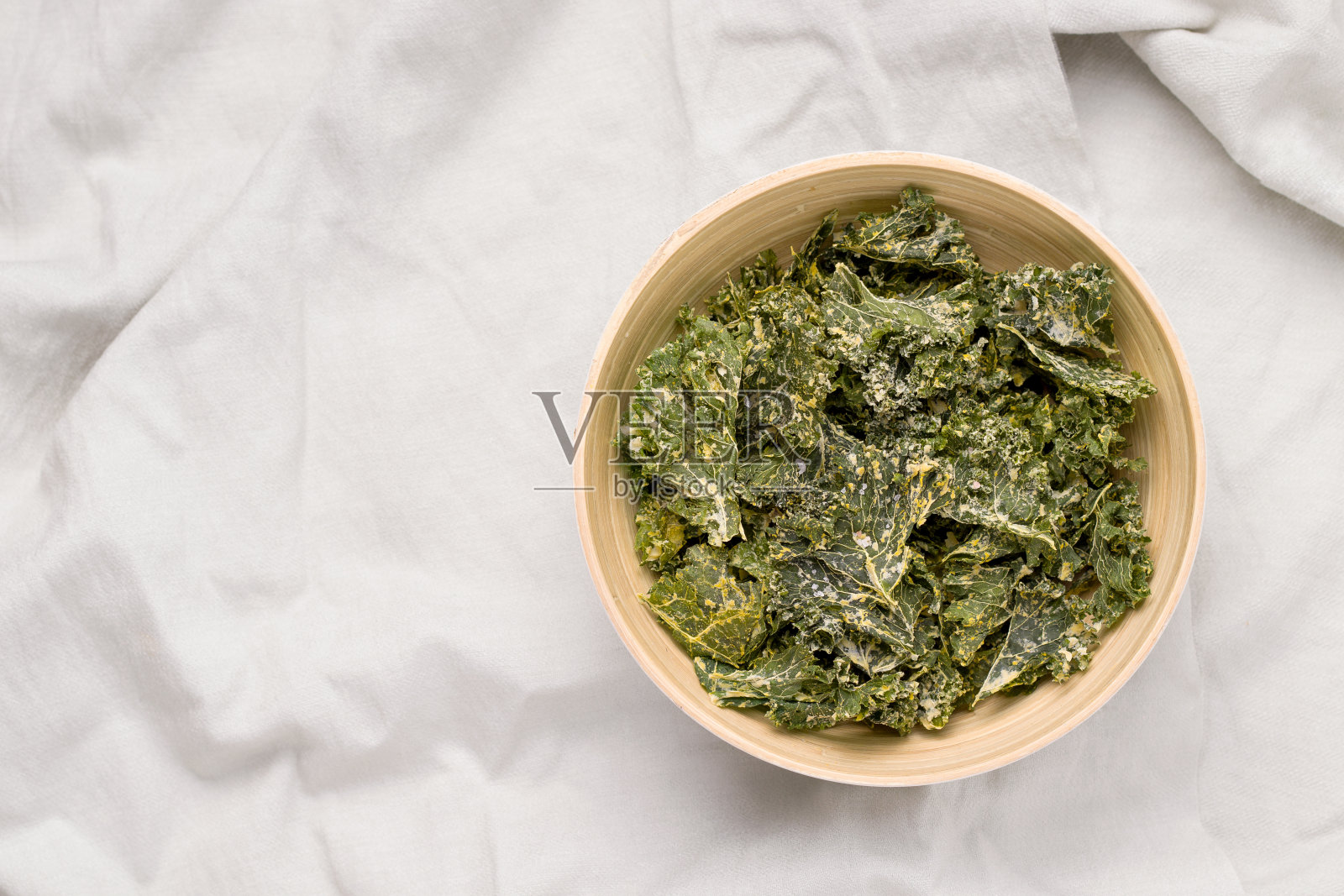 灰色背景下碗里的羽衣甘蓝片。从以上观点。本空间照片摄影图片