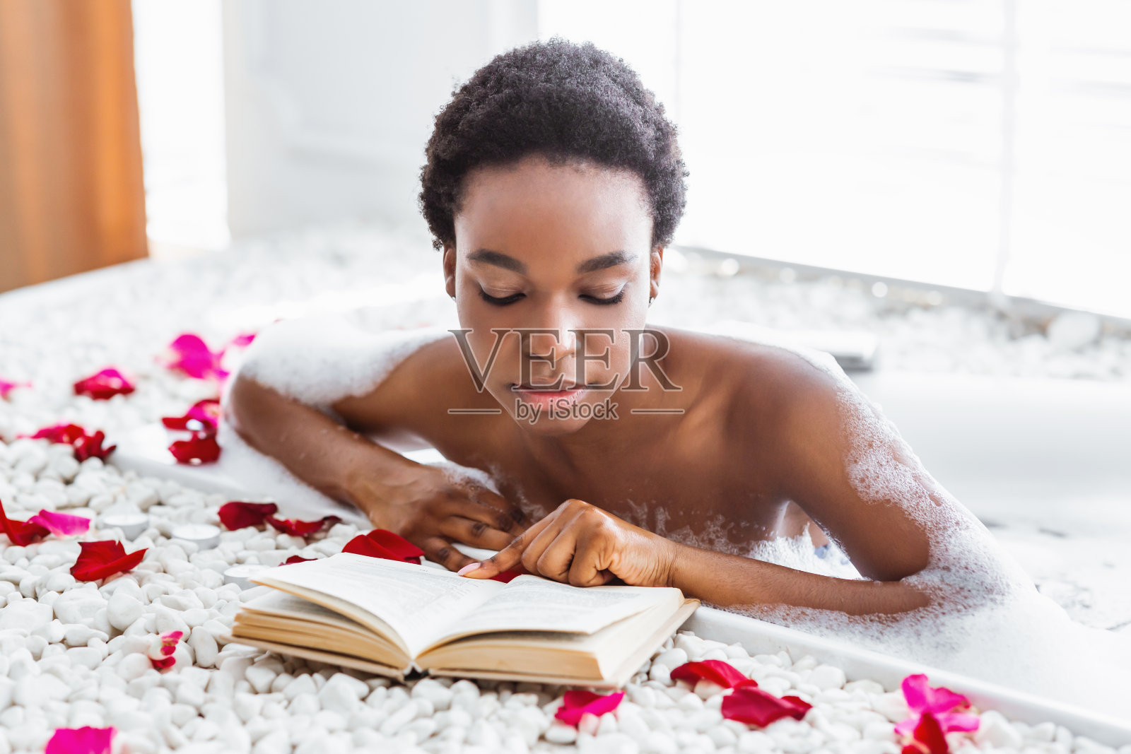 最喜欢的书和放松。专心读书的女孩,坐在浴室里泡着泡沫照片摄影图片
