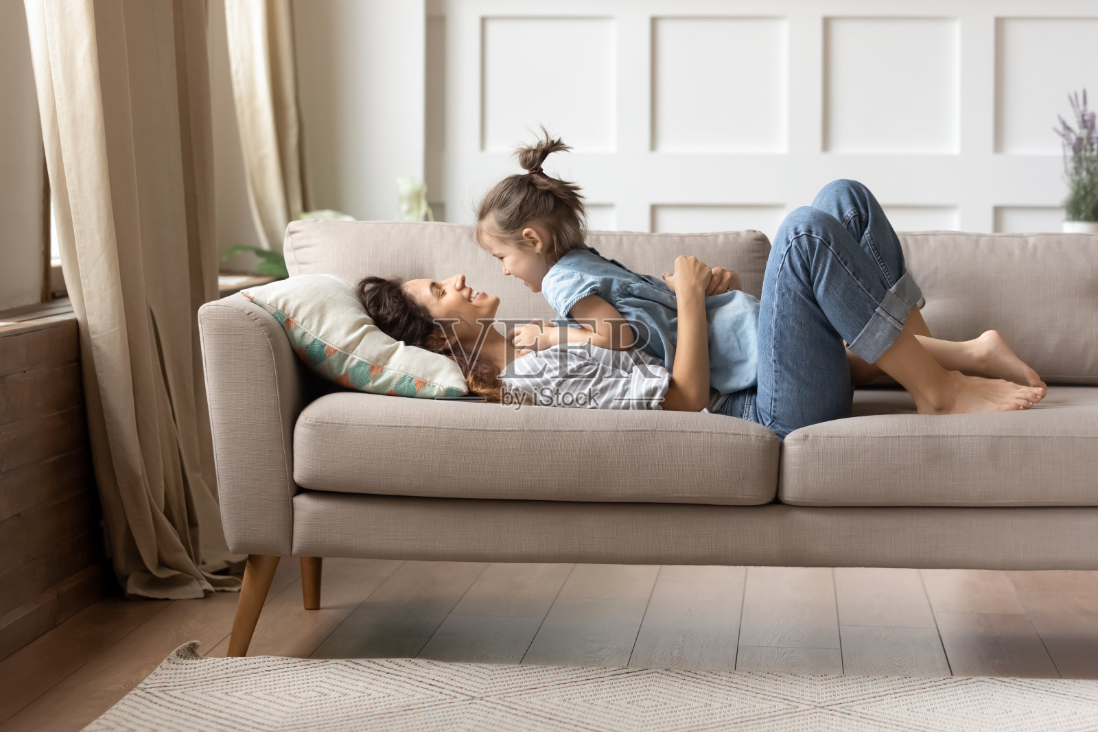 沙发上躺着快乐的妈妈和她快乐的小女儿照片摄影图片