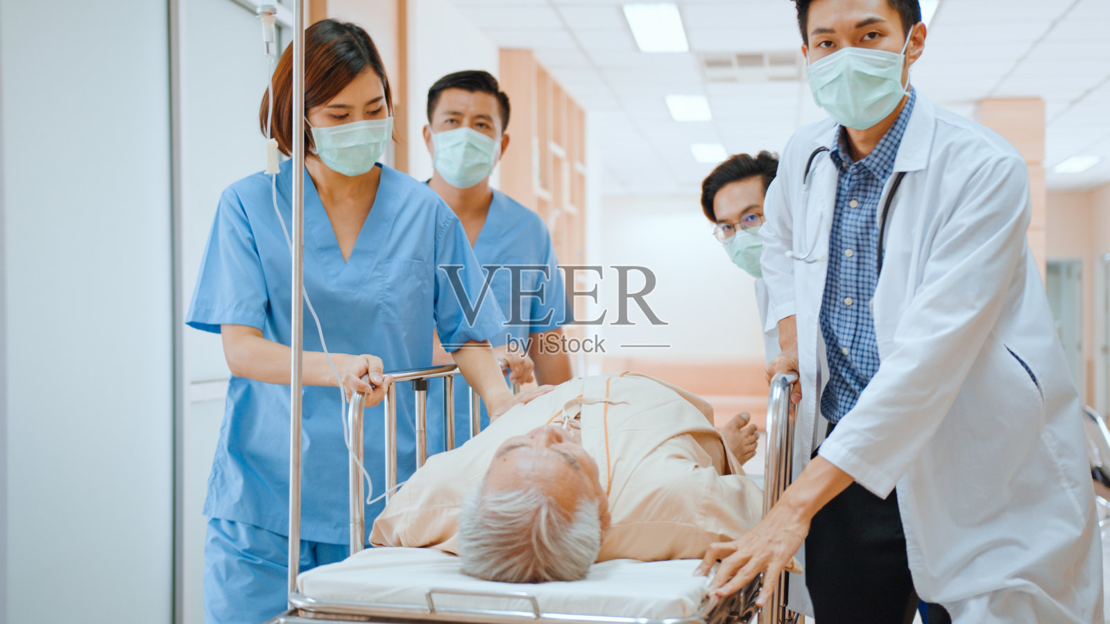 亚洲急救医生和护士小组戴口罩,推急救担架,运送医院老年病人。医疗护理服务,或医疗救援队的运作概念照片摄影图片