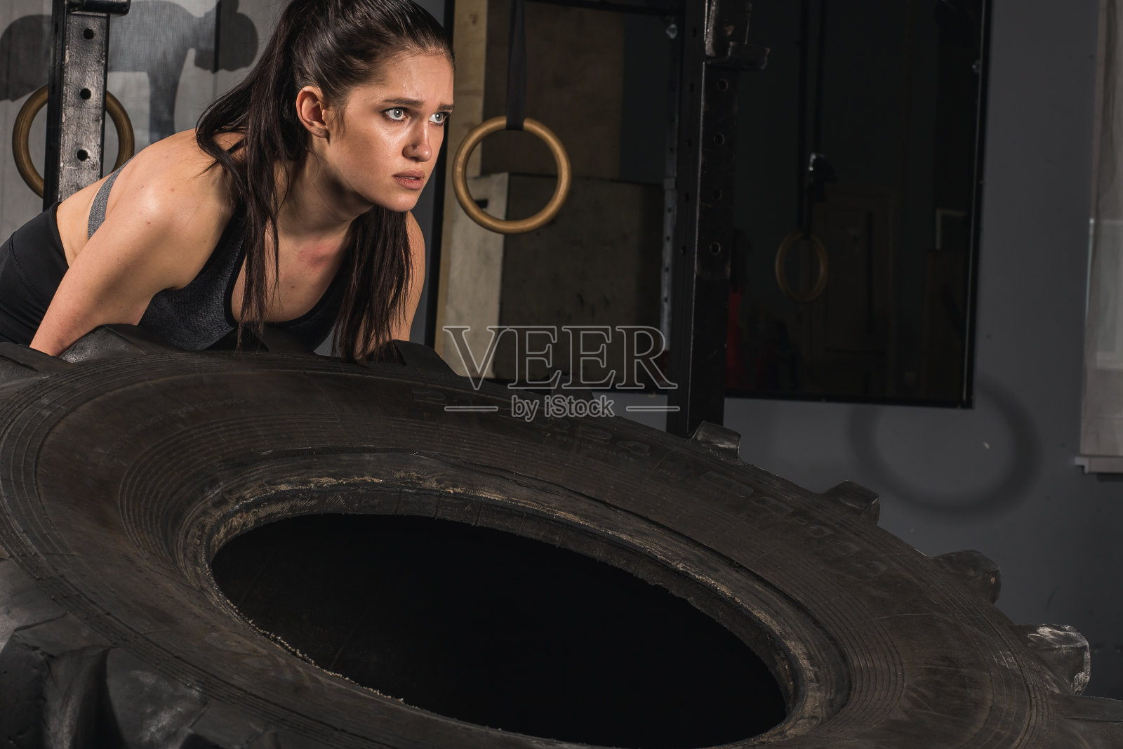 坚强的女孩在健身房甩轮胎。照片摄影图片