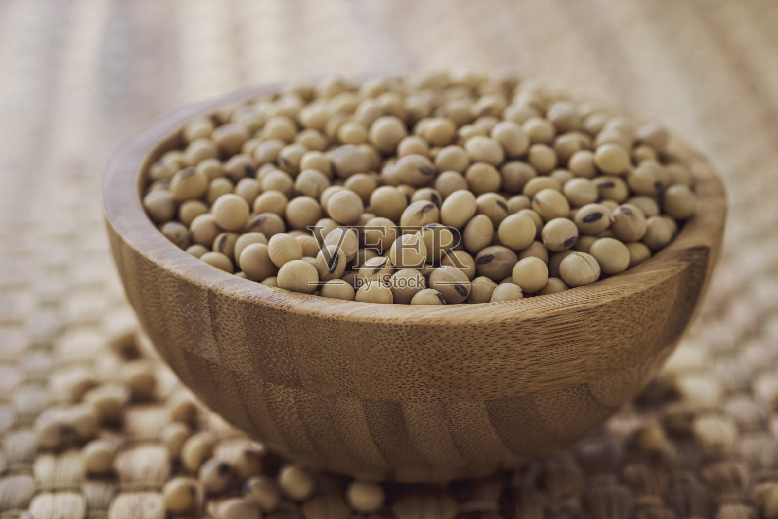 特写的新鲜干大豆种子在木碗上的水葫芦垫。照片摄影图片