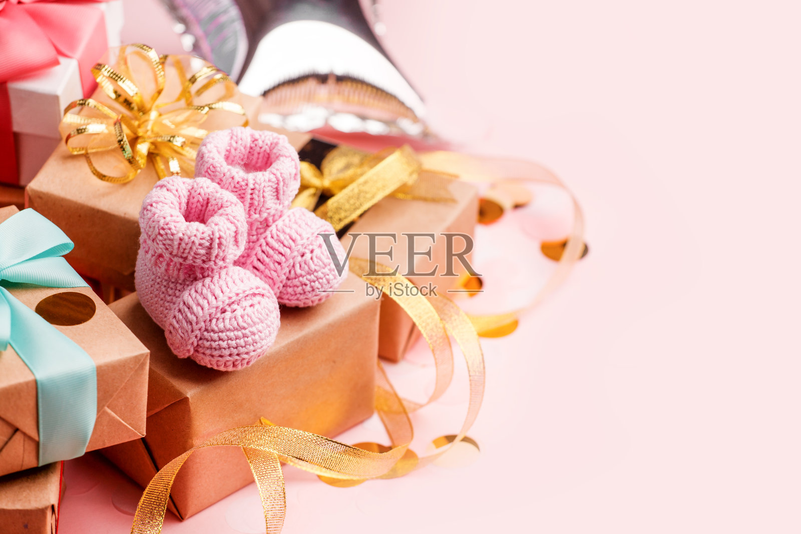 美丽的组成与粉红色的婴儿靴和礼物盒在粉红色的背景。婴儿送礼会的概念,一周岁的节日贺卡,复印空间照片摄影图片