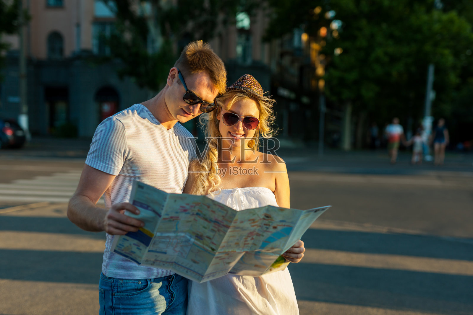 暑假——一对戴着太阳镜,带着地图在城市里微笑的夫妇照片摄影图片