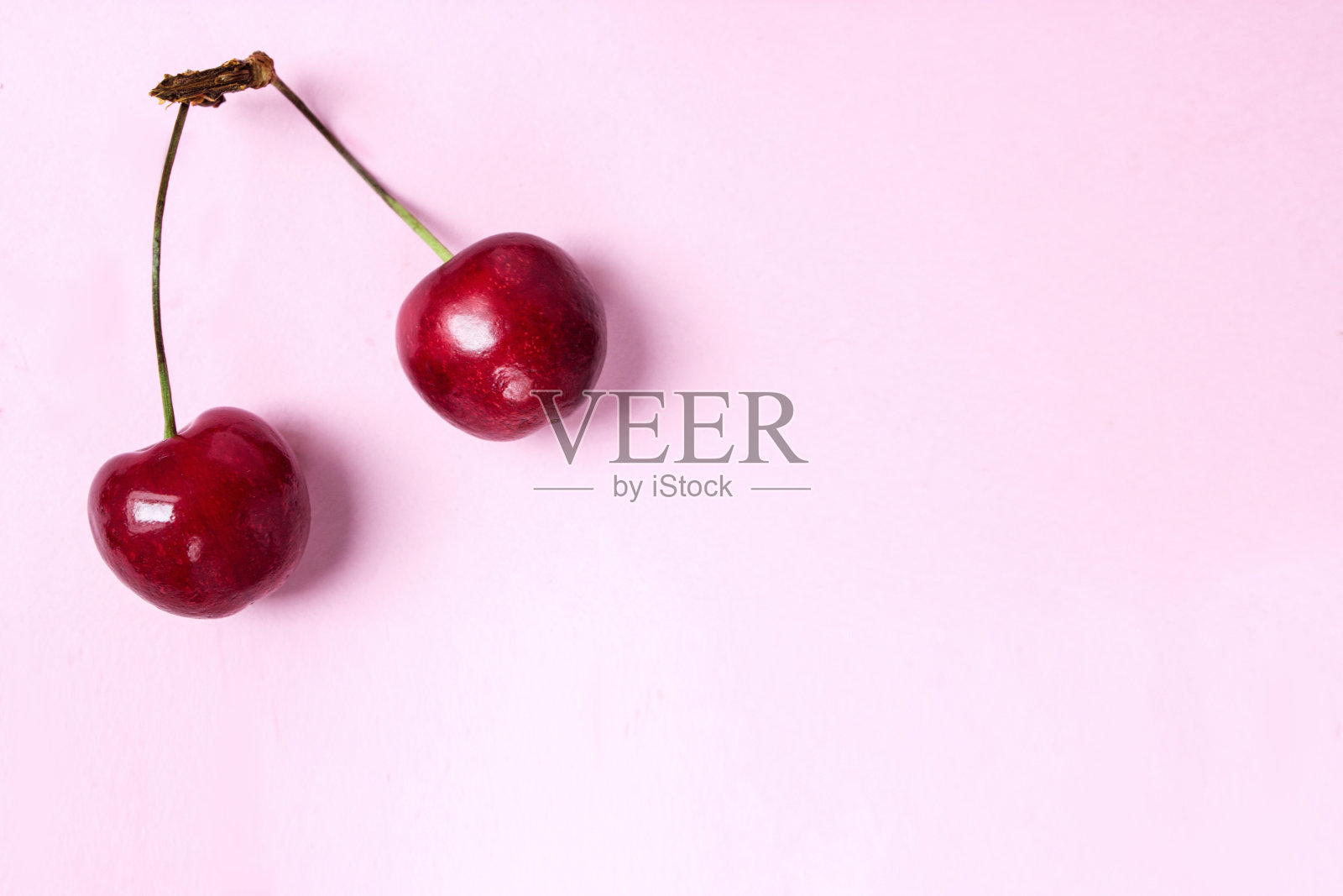 红色浆果美味多汁的樱桃躺在粉红色的左上角。照片平放在粉红色的背景上,有自由的空间。照片摄影图片