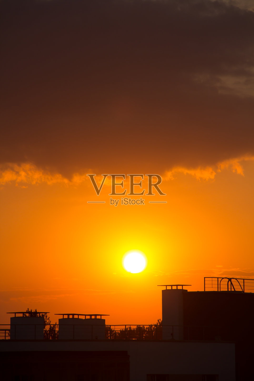 在一个炎热的夜晚,橙色的夕阳映衬着房屋的剪影照片摄影图片