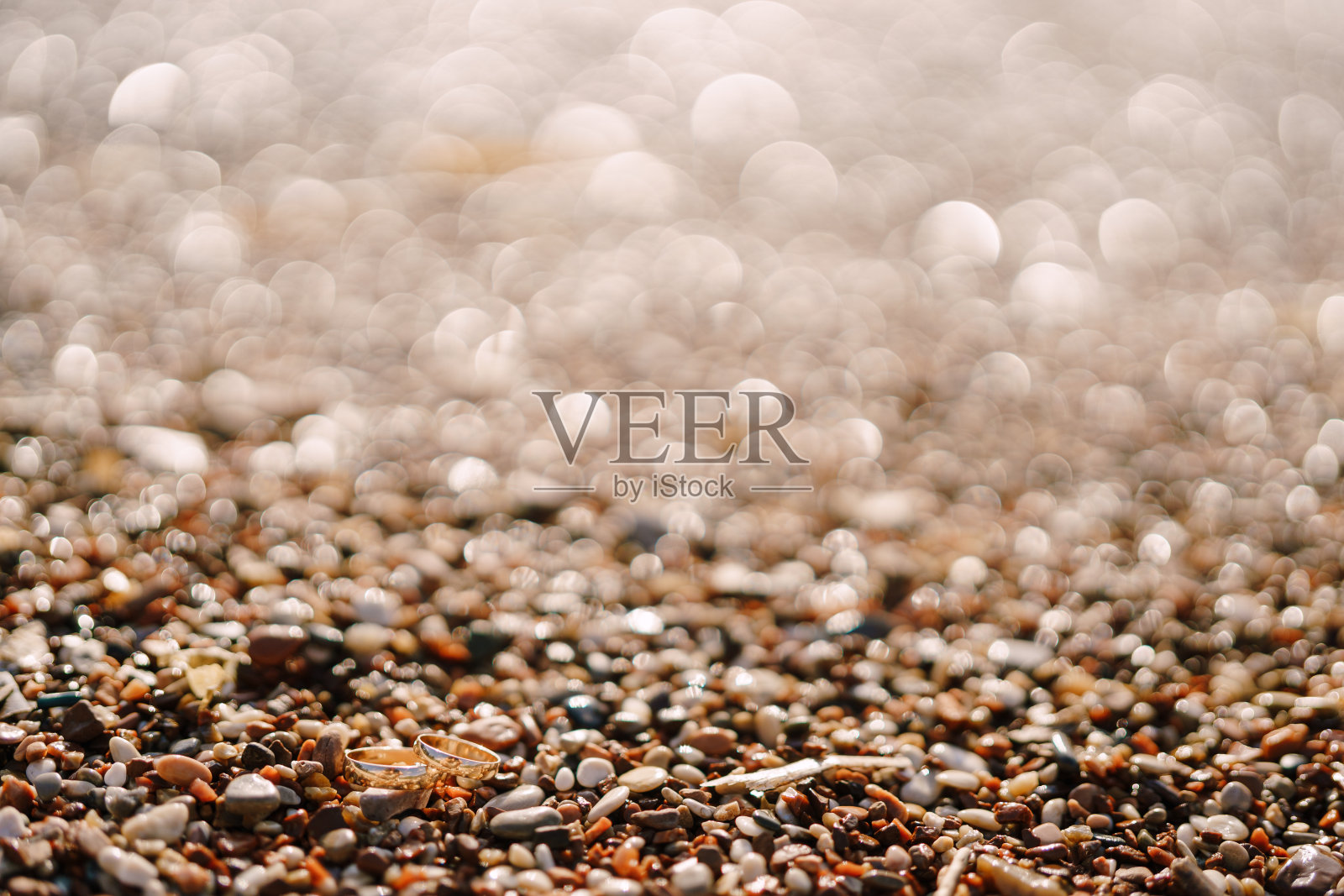 新娘和新郎的戒指是在模糊的背景上用鹅卵石做成的黄金。照片摄影图片