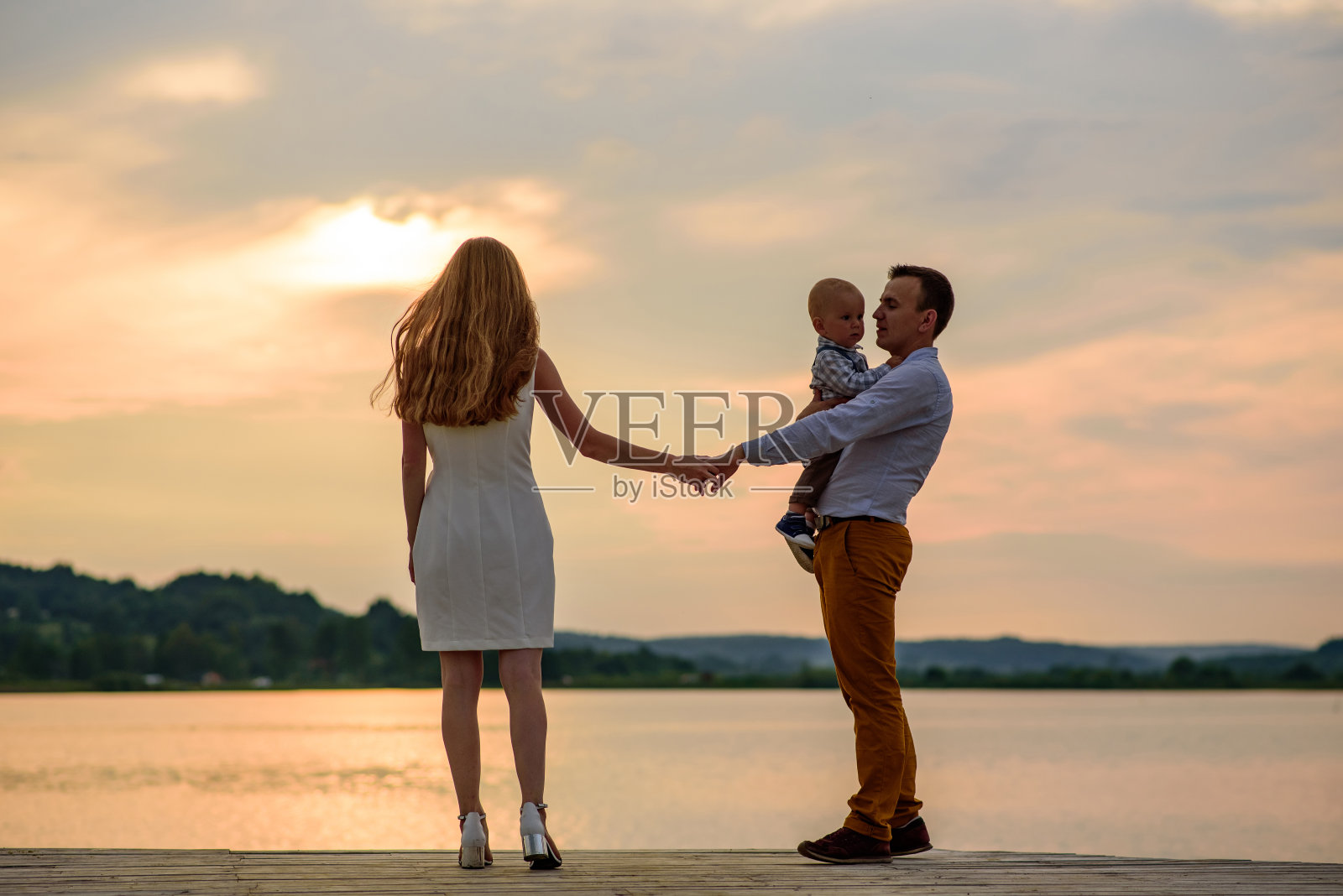 爸爸妈妈和他们一岁的儿子。父亲一手牵着儿子,一手牵着妻子。照片摄影图片