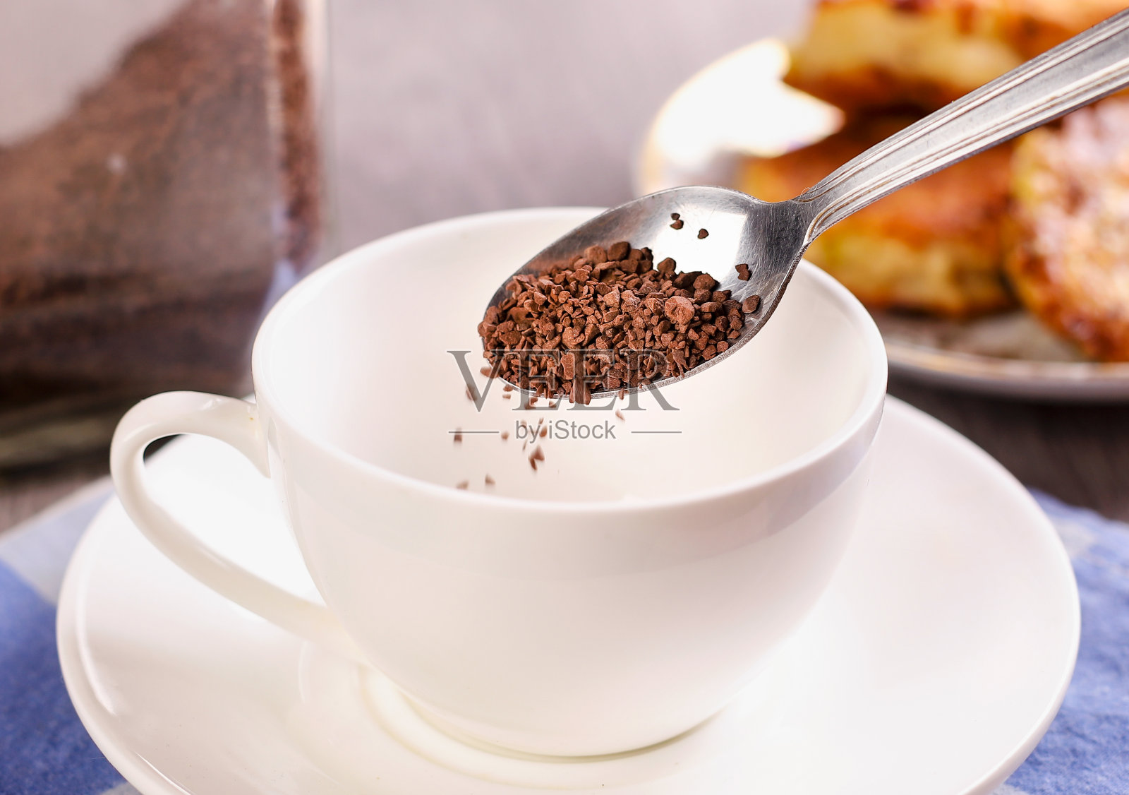 磨碎的咖啡从勺子倒进桌子背景上的杯子里照片摄影图片