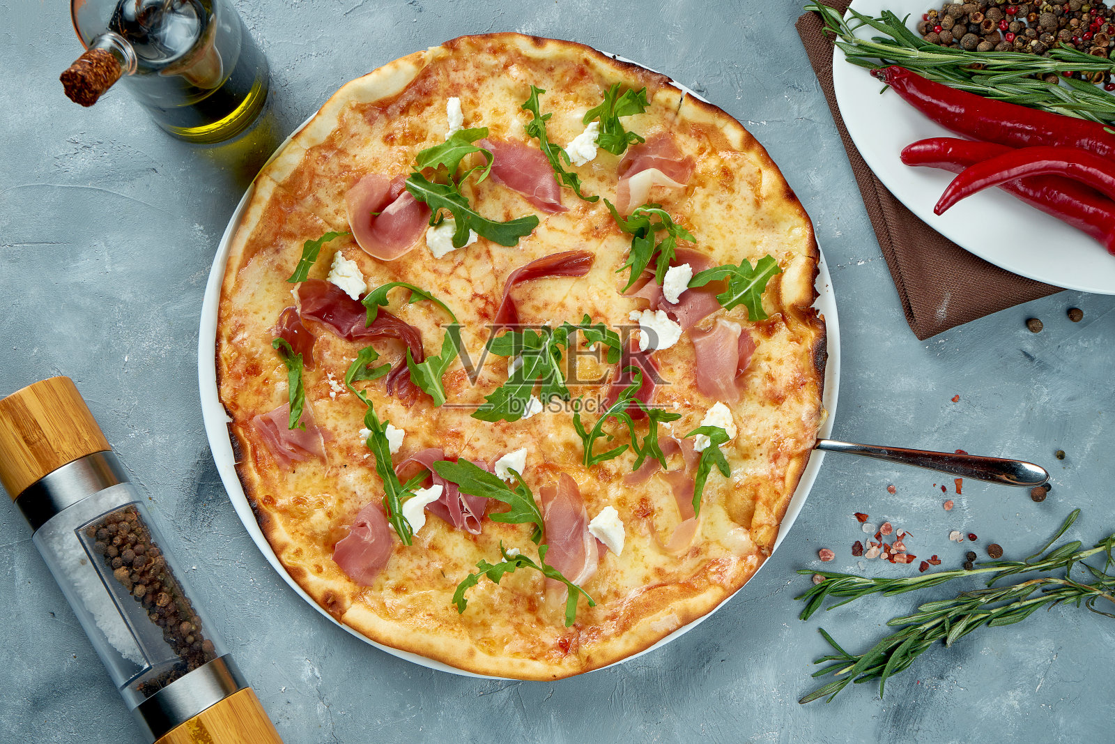 灰色背景上有火腿、芝麻菜和奶油奶酪的意大利披萨。俯视图,食物平放照片摄影图片