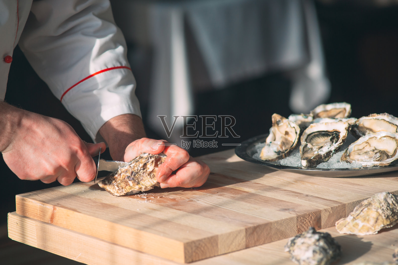 打开中空扁平的牡蛎。厨师在餐厅里开牡蛎。照片摄影图片