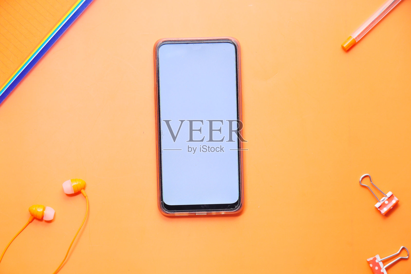 俯视图智能手机和办公文具在橙色的背景照片摄影图片