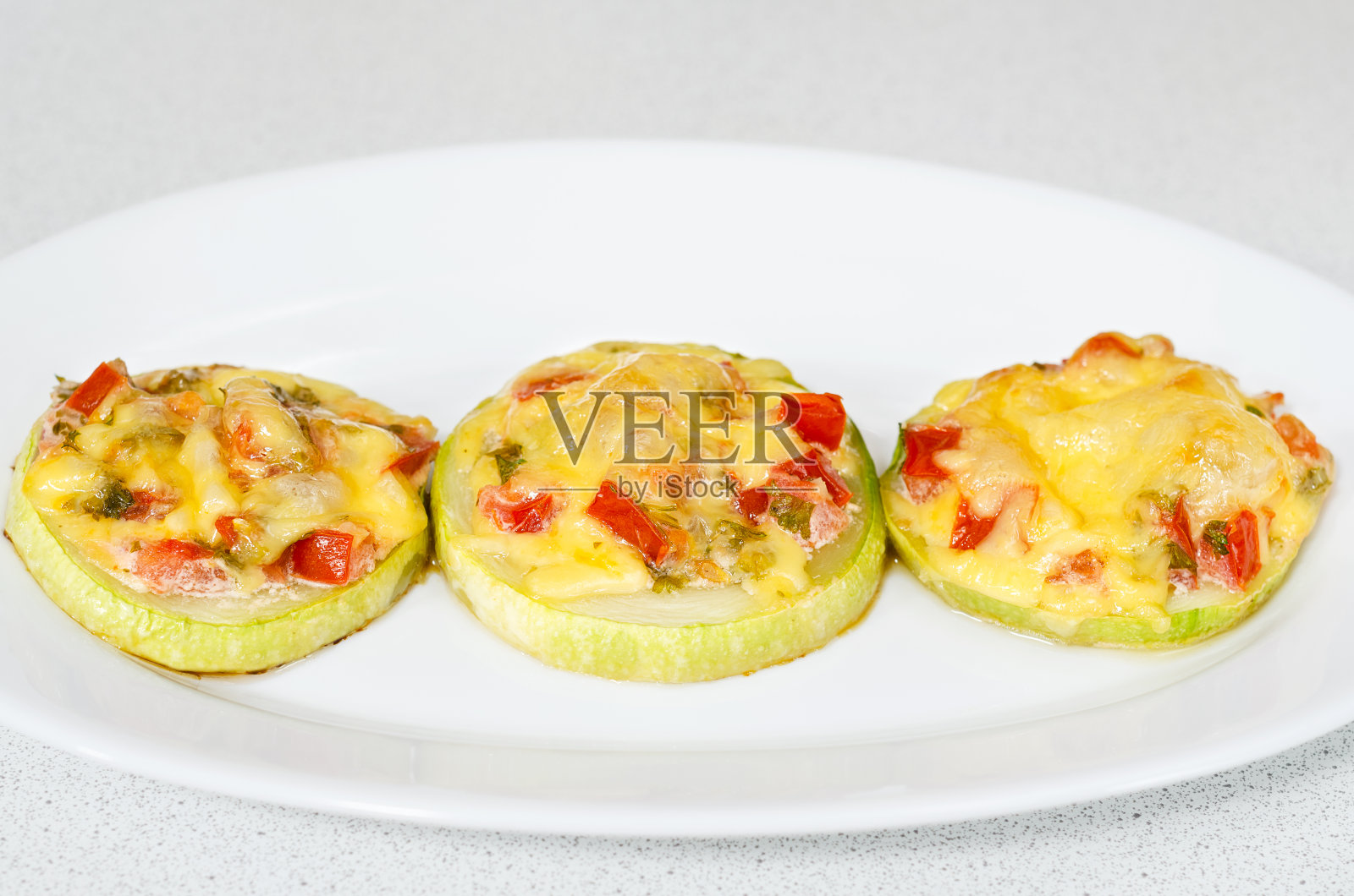 烤西葫芦里塞满了蔬菜和香草,上面撒上奶酪照片摄影图片