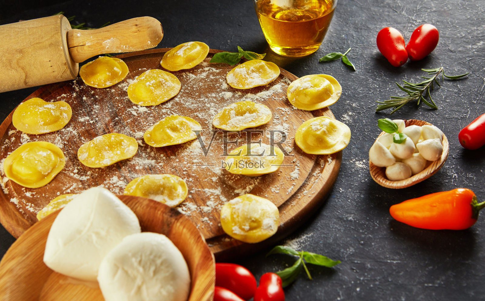 深色背景上搭配面粉、圣女果、葵花籽油和罗勒的美味生意式饺子照片摄影图片